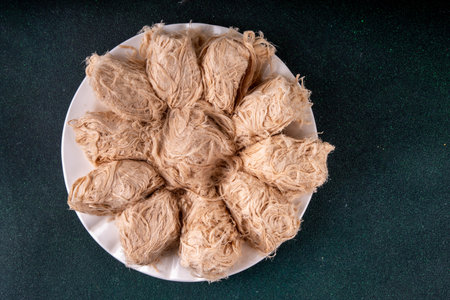 Traditional Asian sweets Pishmaniye, also known as Pashmak, Dragon's Beard, or Kkul Tarae, thread-like hair halvah, with nutty flavor, on a plate, copy spaceの写真素材
