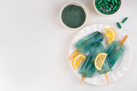 Vegan protein and superfood dessert, Frozen spirulina water lollipops, sweet spirulina smoothie popsicles with lemon, low-calorie healthy gelato on sticksの写真素材