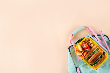 Back to school. Healthy school meal, children packed lunch box with fruit, berry, nuts, sandwich with vegetables. Kids diet snack food with education school supplies, bright blue background top viewの写真素材