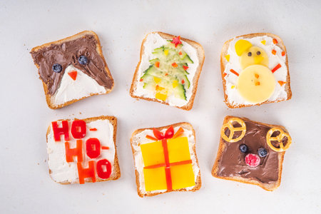 Christmas funny creative toasts sandwich for kids breakfast. Homemade Christmas morning sandwiches in form of gift, Christmas tree, deer, snowman, penguin, with cheese, fruit, chocolate, vegetablesの写真素材