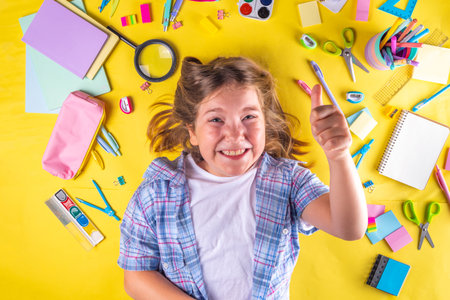 Cute emotional girl ready to back to school with various school supplies, education accessories on bright yellow backgroundの写真素材