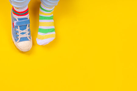 Odd Socks Day, Lonely Sock Day.  Anti-Bullying Week, Down syndrome awareness. Child legs wearing different pair of mismatched socks on high-colored background copy spaceの写真素材