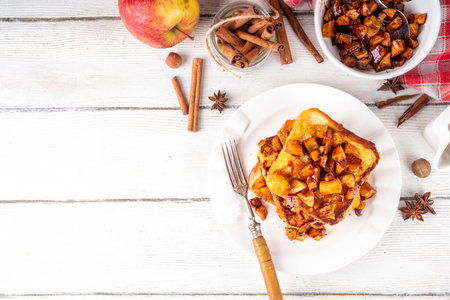 Sweet breakfast Apple Pie French Toast. Tasty delicious Stuffed French Toast with apple pie filling, cinnamon and ice cream scoop on top, with spices and fresh apples on table backgroundの写真素材