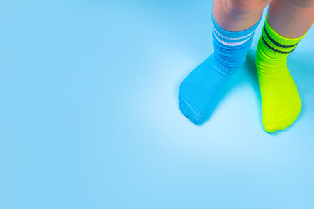 Odd Socks Day, Lonely Sock Day.  Anti-Bullying Week, Down syndrome awareness. Child legs wearing different pair of mismatched socks on high-colored background copy spaceの写真素材