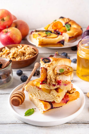 Tasty fruit dessert Focaccia. Sweet viral italian Focaccia open pie, with various seasonal autumn and summer fruits - plum, apple, figs, apricot, blueberry, peach and nuts, with spices and honeyの写真素材