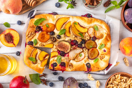 Tasty fruit dessert Focaccia. Sweet viral italian Focaccia open pie, with various seasonal autumn and summer fruits - plum, apple, figs, apricot, blueberry, peach and nuts, with spices and honeyの写真素材
