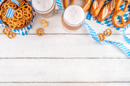 Oktoberfest greeting card background with two beer glasses, salted snack and pretzels. Oktoberfest bar, cafes menu on white wooden table, with checkered napkin and decor in Oktoberfest holiday styleの写真素材