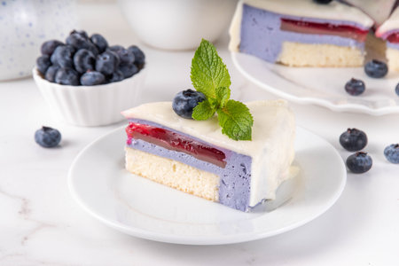 Tasty berry layered mousse tart cake with blueberries and white with white chocolate glaze, cut into...