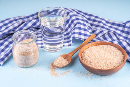 Whole Psyllium Husk in spoon, bowl and jar, with glass of water, natural alternative to pills or injections for weight loss. Additional fiber source, adsorbent, dietary supplement for healthy eatingの写真素材