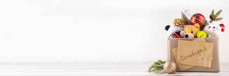 Donating gifts and toys to charity for Christmas holiday concept. Tradition holiday toys drive, cardboard box full with with kids toys, gifts, Christmas decorations, baubles and sweets, copy spaceの写真素材