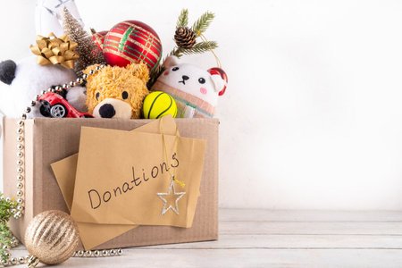 Donating gifts and toys to charity for Christmas holiday concept. Tradition holiday toys drive, cardboard box full with with kids toys, gifts, Christmas decorations, baubles and sweets, copy spaceの写真素材