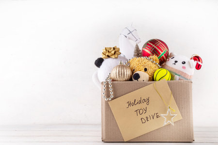 Donating gifts and toys to charity for Christmas holiday concept. Tradition holiday toys drive, cardboard box full with with kids toys, gifts, Christmas decorations, baubles and sweets, copy spaceの写真素材