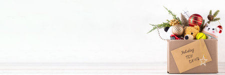 Donating gifts and toys to charity for Christmas holiday concept. Tradition holiday toys drive, cardboard box full with with kids toys, gifts, Christmas decorations, baubles and sweets, copy spaceの写真素材