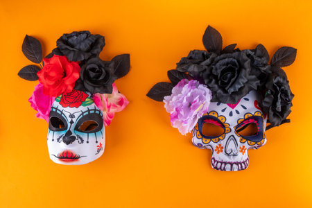 Dia de los muertos holiday background with black autumn flowers, and Mexican Day of the Dead masks. on bright orange background copy spaceの写真素材