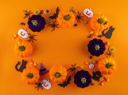 Happy Halloween holiday background with colorful pumpkins and holiday symbols decor, spiders, witch hat, bat, black cats, ghost, candies, candy corn on bright background top view copy spaceの写真素材