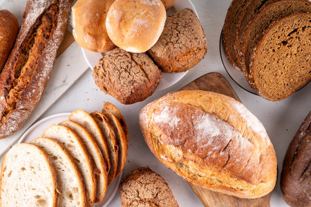 Set of various Prebiotic Bread with live bacteria, prebiotics, fiber for gut health. Healthy alternative to regular bread, different rye, white, grain bread and buns on white table backgroundの写真素材