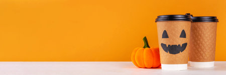 Halloween themed take away craft paper coffee cup with pumpkin jack o lantern face on bright orange background, autumn and Halloween menu background mockupの写真素材