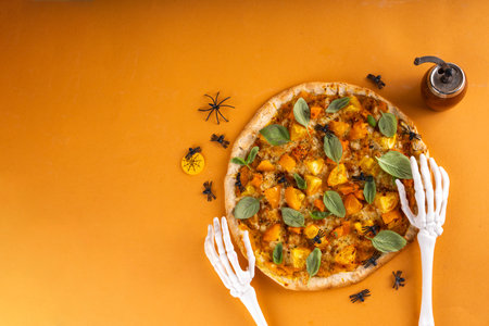 Homemade vegetable pizza  for Halloween party, Margarita with pumpkin sauce, pumpkin squash chunks and tomatoes, with Halloween decoration, background for Halloween food delivery restaurant menuの写真素材