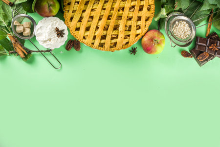 Autumn cooking baking background with sweet apple pie. Traditional american apple pie with fresh apples, cinnamon, spices, baking ingredients, top view copy space on light green backgroundの写真素材