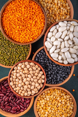 Various dried  beans, lentils, mung, chickpea, pea  assortment in wooden bowls. Legumes on white table top view. Vegan protein sources food, copy spaceの写真素材