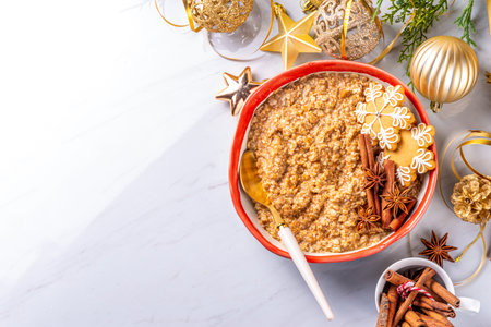 Christmas morning gingerbread oatmeal breakfast. Spice sweet oatmeal with gingerbread crumbs, cinnamon and honey, on festive decorated background copy spaceの写真素材