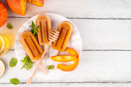 Sweet tasty pumpkin and honey popsicles ice cream. Frozen sorbet gelato on sticks, made with pumpkin squash puree and golden honey, delicious autumn dessert, copy spaceの写真素材