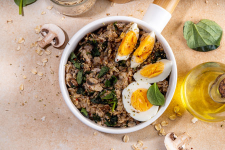Tasty savory overnight oatmeal. Tasty non-sweet breakfast oats with spinach, mushrooms and eggs, on beige background ingredients for cookingの写真素材