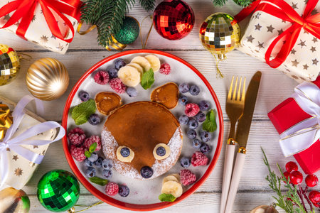 Funny and cute Christmas little fox pancakes on a red white plate decorated with fresh berry, fruit and powdered sugar, children's Christmas breakfast or brunch ideaの写真素材