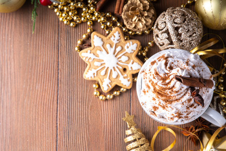 Hot chocolate, latte coffee or eggnog cocktail with whipped cream and cinnamon stick in white ceramic cup on Christmas, New Year decorated tableの写真素材