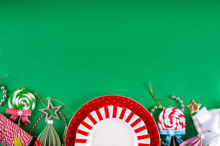Christmas and New Year cutlery background, holiday table setting, festive dinner brunch invitation menu. Red white candy cane styled plate and Christmas baubles on bright green backgroundの写真素材