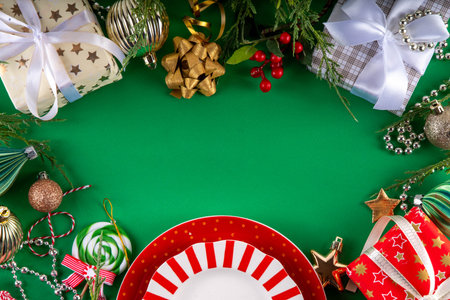 Christmas and New Year cutlery background, holiday table setting, festive dinner brunch invitation menu. Red white candy cane styled plate and Christmas baubles on bright green backgroundの写真素材
