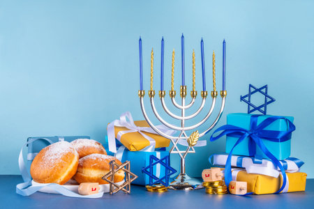 Happy Hanukkah greeting card background. Jewish New Year holiday flat lay with traditional symbols of hanukkah festival, menorah with festive candles, donuts and decorations copy spaceの写真素材