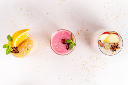Autumn winter spicy fruit smoothie set. Various flavor tasty smoothie drinks in 3 glasses with yogurt, oats, seasonal fruits - apple, orange, cranberry, with anise and cinnamonの写真素材