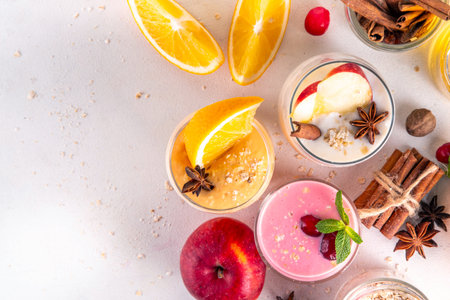 Autumn winter spicy fruit smoothie set. Various flavor tasty smoothie drinks in 3 glasses with yogurt, oats, seasonal fruits - apple, orange, cranberry, with anise and cinnamonの写真素材