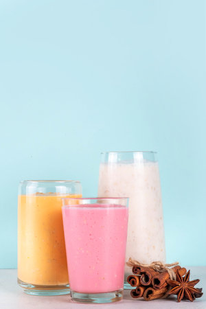 Autumn winter spicy fruit smoothie set. Various flavor tasty smoothie drinks in 3 glasses with yogurt, oats, seasonal fruits - apple, orange, cranberry, with anise and cinnamonの写真素材