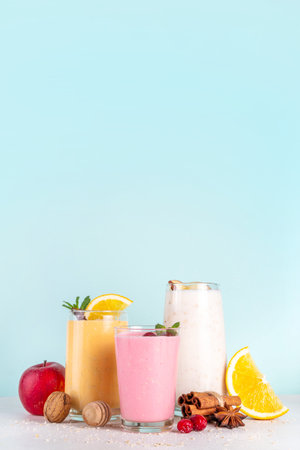 Autumn winter spicy fruit smoothie set. Various flavor tasty smoothie drinks in 3 glasses with yogurt, oats, seasonal fruits - apple, orange, cranberry, with anise and cinnamonの写真素材