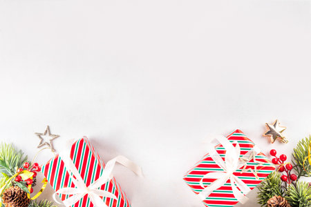 White background with Christmas and New Year festive border contains gift boxes, Christmas fir tree branches, decorations and holiday baublesの写真素材