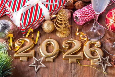 Festive Christmas and New Year 2026 background with champagne glasses, holiday baubles, Christmas...