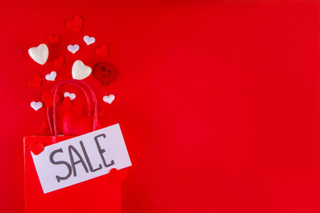 Valentine day sale and shopping background . Red paper shopping bag with text sale, white, red, gold hearts. Simple minimal Valentines greeting card, invitation, marketing promo mockup copy spaceの写真素材