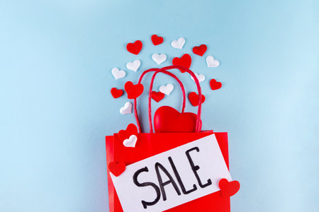 Valentine day sale and shopping background . Red paper shopping bag with text sale, white, red, gold hearts. Simple minimal Valentines greeting card, invitation, marketing promo mockup copy spaceの写真素材