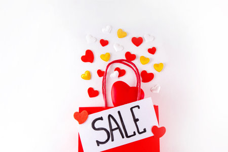 Valentine day sale and shopping background . Red paper shopping bag with text sale, white, red, gold hearts. Simple minimal Valentines greeting card, invitation, marketing promo mockup copy spaceの写真素材