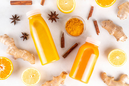 Ginger turmeric immunity shot, tasty vitamin citrus fruit infused drink in small bottles, made with orange, lemon, turmeric, ginger, cinnamon, spices, alternative medicine flu and cold remedy beverageの写真素材