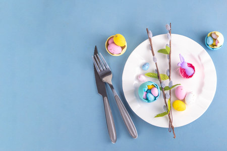 Spring Easter holiday menu table setting, cutlery and plate on pastel blue background with checkered...