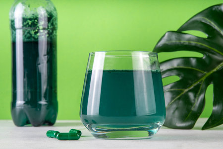 Liquid Chlorophyll Drink. Bottle and Glass with Green Chlorophyll Water, Chlorophyll powder and pills, healthy trendy vitamin beverageの写真素材