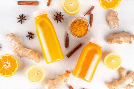 Ginger turmeric immunity shot, tasty vitamin citrus fruit infused drink in small bottles, made with orange, lemon, turmeric, ginger, cinnamon, spices, alternative medicine flu and cold remedy beverageの写真素材