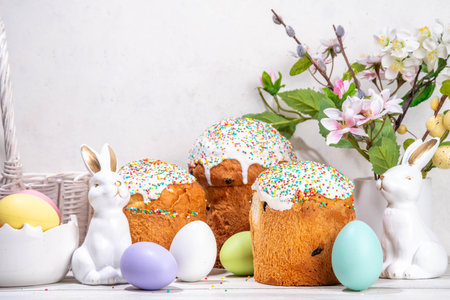 Tasty Glazed Easter cakes with sugar decor, colorful eggs basket, ceramic rabbits and spring flowers...