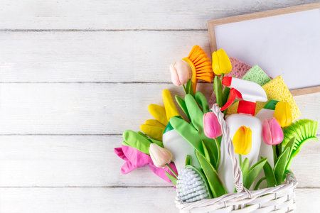 Spring cleaning background with spring flowers and cleaning utensils in white basket, Various household supplies, bottles, accessories, with blossom tulips, promotion copy spaceの写真素材