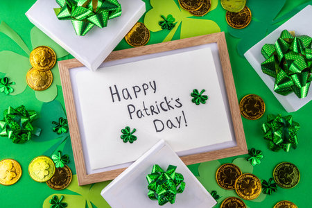Shamrock saint patrick's day bright high-colored background, St. Patrick's holiday flatlay with party gift boxes, decor, shamrock and gold coins on green backgroundの写真素材