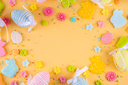 Cute and bright pastel colored Easter eggs and bunny background. Pink. blue, yellow colored bunny rabbits, eggs and flowers sugar sprinkles on light yellow backgroundの写真素材
