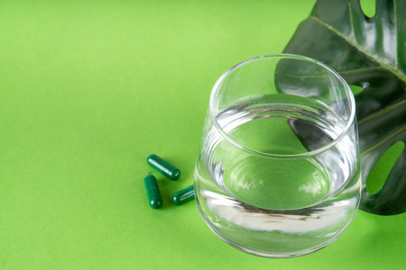 Liquid Chlorophyll Drink. Bottle and Glass with Green Chlorophyll Water, Chlorophyll powder and pills, healthy trendy vitamin beverageの写真素材